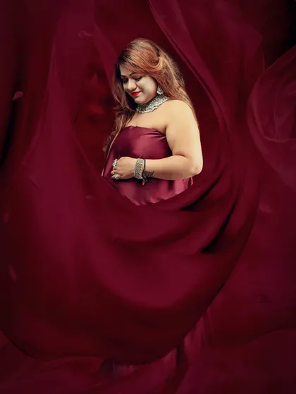 This artistic portrait uses deep red fabric to envelop the mom-to-be, creating a soft, womb-like effect that is both intimate and visually stunning.