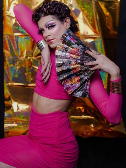 This pose showcases the complete drag look, from the dramatic makeup to the vibrant outfit and confident attitude.
