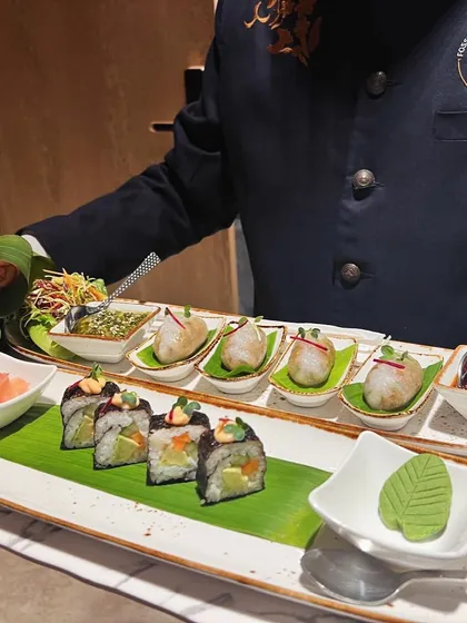 We present a journey through Pan-Asian flavors on a single platter. This arrangement features delicate vegetable sushi and savory dim sum, showcasing our expertise in diverse global cuisines.