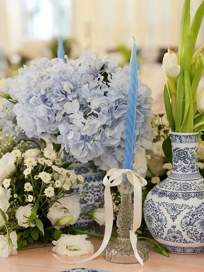 A close-up of a chinoiserie vase filled with blue hydrangeas and white flowers.