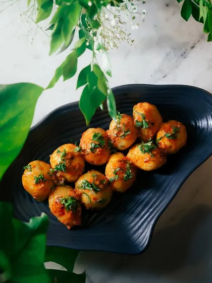 A different view of the Honey Tamarind Potatoes, showcasing the glossy sauce and fresh garnish. This is a standout vegetarian dish for any event.
