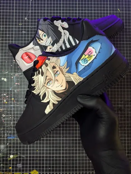 Holding up the completed Doma and Obanai Iguro custom Air Force 1s. The details, from Doma's rainbow eyes to Obanai's snake, are all carefully hand-painted.