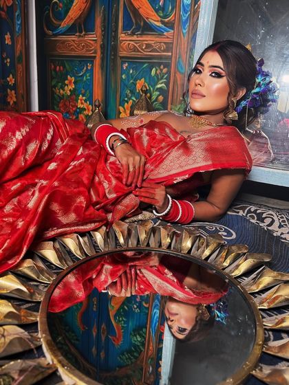 A classic Bengali bridal look, complete with a perfectly draped red saree and a beautiful reflection.