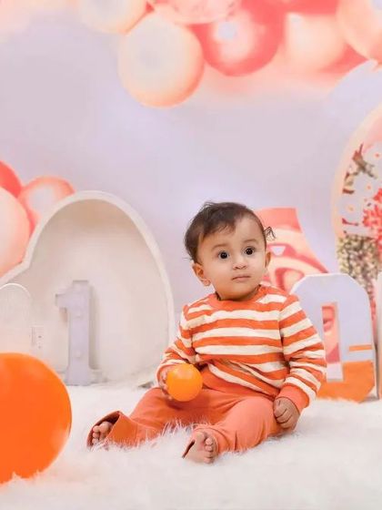 An orange-themed first birthday shoot with matching balloons and props. This setup provides a bright, cheerful, and unique color palette for the celebration.