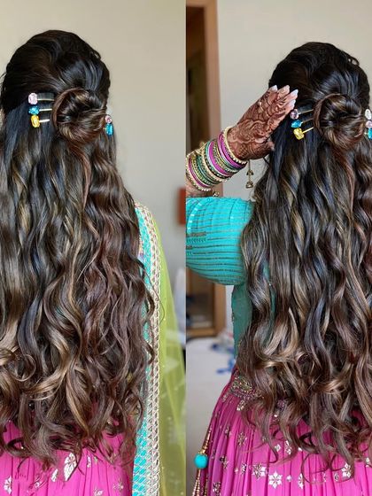 A half-up top knot with beachy waves, perfect for a Mehendi. The colorful clips add a playful touch to this modern and chic hairstyle.