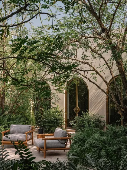 A quiet seating area at the Dua Villa, nestled within a lush garden. This space exemplifies our goal of blurring the lines between indoor and outdoor living, creating verdant sanctuaries for slow, contemplative moments.