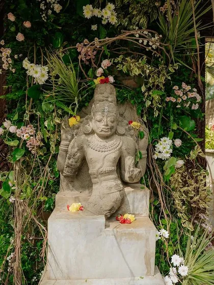 A stone deity statue adorned with flowers, a spiritual and beautiful focal point for a wedding ceremony.