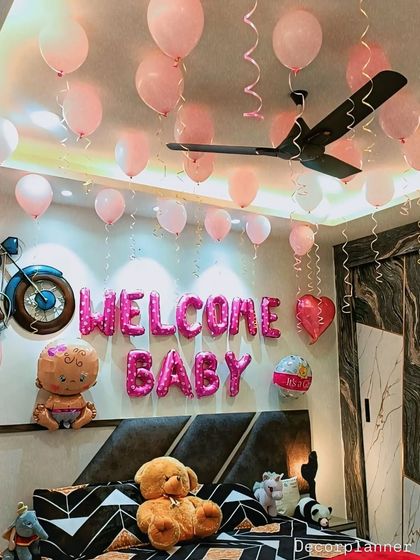 A close-up of the "Welcome Baby" balloon arrangement over the bed. The mix of foil and latex balloons adds variety and visual interest to the simple and sweet setup.
