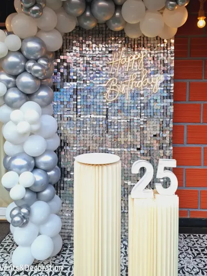 Celebrating a 25th birthday with a glamorous silver shimmer wall. The white and silver balloon arch and light-up marquee numbers add to the chic and festive atmosphere.