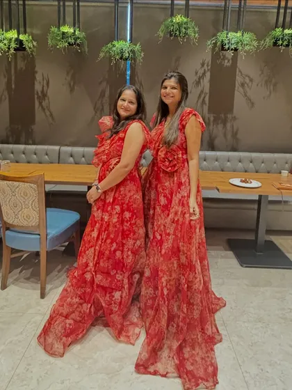 Twinning is winning. Two clients are seen here in my red floral organza gowns, showing how you can coordinate with a friend for a wedding or party.