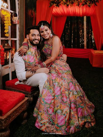 A happy, candid moment between Arya and Vishnu during their wedding celebration. The vibrant colors of their outfits and the festive decor create a lively scene.