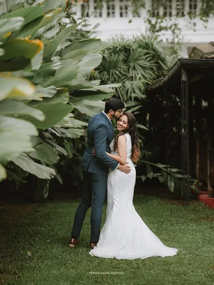 A loving embrace in a garden, the groom's kiss on the bride's head a gesture of pure affection.