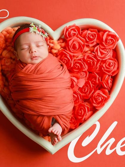 The "Rose Cherry" setup, featuring a baby swaddled in red, nestled in a heart bowl. The vibrant colors make this a very popular and eye-catching choice.