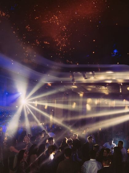 The dance floor illuminated by dramatic spotlights. This atmospheric shot captures the epic scale and energy of a grand wedding reception.