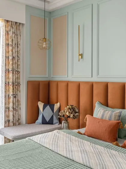 This bedroom from the Zen Residence features a bold, channel-tufted headboard in a rich tan color, which contrasts beautifully with the soft mint green paneled wall.