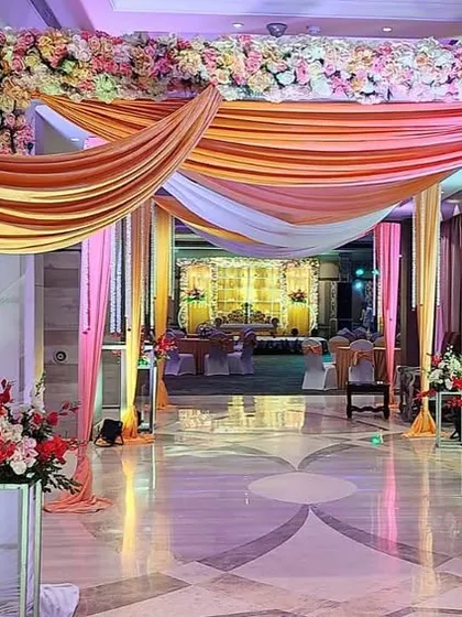 A grand entrance at The Suryaa Hotel, featuring draped fabric in peach and pink, creating a soft and luxurious welcome.