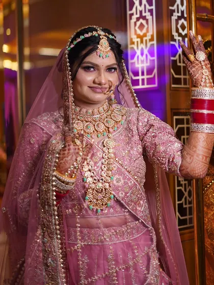 A confident pose from the bride, showcasing her full attire and heavy jewelry. The purple lighting in the background makes her stand out.