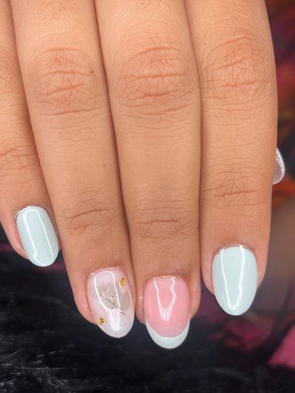 Pastel nails with a delicate floral decal and gold foil accents.
