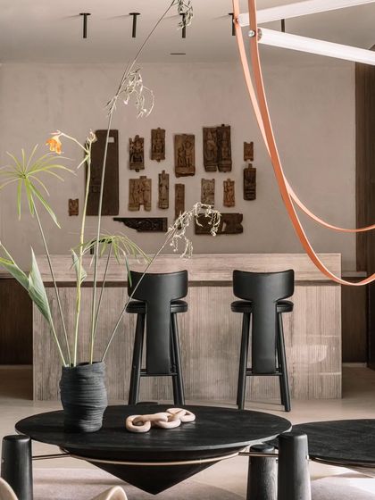 The bar area within the living room, featuring a travertine bar and a collection of antique wooden printing blocks as wall art. The design combines modern forms with traditional, textural elements.
