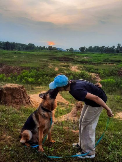 Just a girl and her German Shepherd against a beautiful sunset. Training him to hold a calm 'sit' in an open field like this is a result of consistent, positive practice.