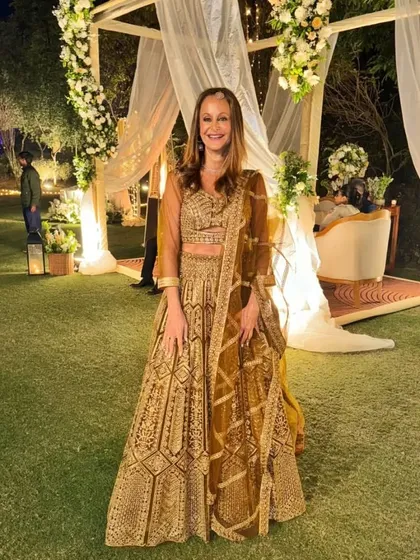 A client looking elegant at an outdoor wedding in our golden-brown lehenga. The outfit is perfect for a sophisticated evening event.