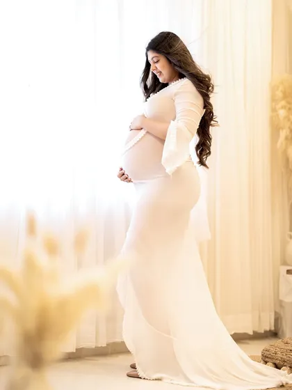 A classic side profile pose to emphasize the beautiful curve of the baby bump, with soft light creating a gentle glow.