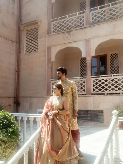 A classic portrait of the couple on a balcony at their palace wedding venue. Their regal poses and coordinated outfits make for a timeless and elegant photograph.