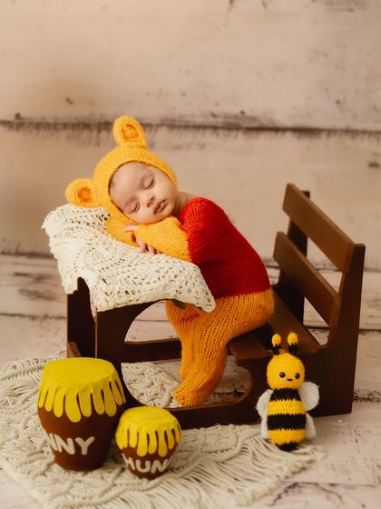 Another take on the Winnie the Pooh theme, this newborn is posed sleeping on a miniature bench, creating an incredibly sweet and story-like image.