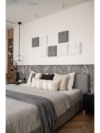 The bed in the master suite is elegantly framed by an Andromeda leather-finish stone backdrop. The layering of textures, from the stone to the bedding and the custom artwork, creates a rich and inviting space.