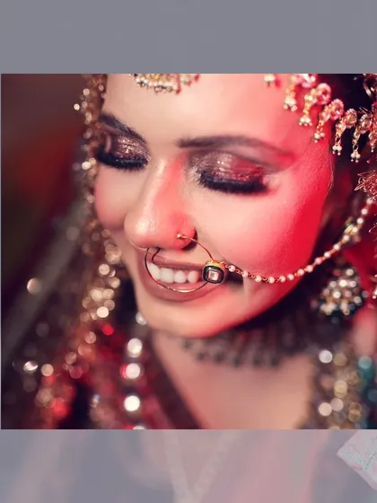 A close-up of the bride's joyful smile on her wedding day. The warm, red lighting adds a traditional and celebratory feel to this beautiful portrait.