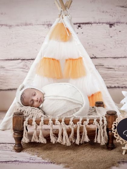 A boho-chic teepee setup with the baby sleeping on a miniature cot. This rustic and adventurous theme is perfect for a modern, stylish newborn shoot.