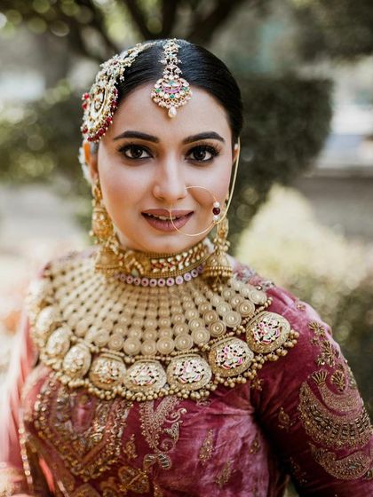 A stunning close-up of a bride with traditional coin-style jewelry. Her makeup is classic and clean, with defined brows and a subtle lip, letting her natural beauty and magnificent jewelry shine.