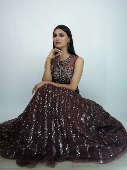 A seated photo showing the full, flowing skirt of the brown sequin gown.