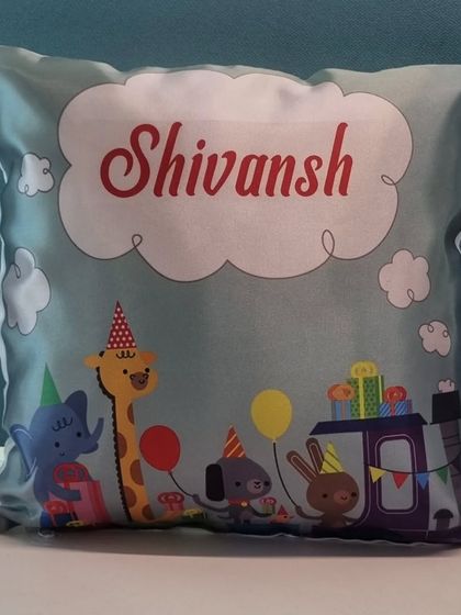 This adorable cushion is perfect for a nursery or kid's room. It features a cute animal train design and is personalized with the name 'Shivansh'.