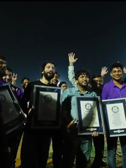 Pure celebration. Members of our team raise their arms and the world record certificates in triumph, a moment of shared success and immense pride.