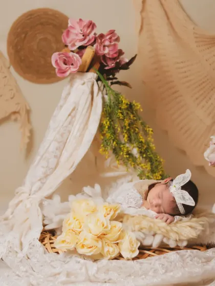 A full view of our floral teepee setup, where the baby sleeps peacefully in a basket adorned with lace, surrounded by yellow and pink flowers.