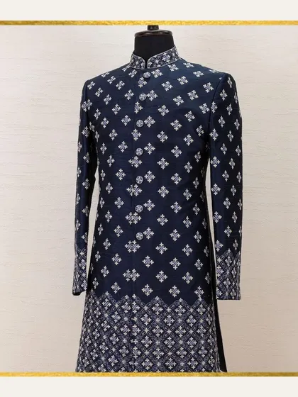A mannequin showcases a navy sherwani with a classic, repeating geometric pattern. This image is a testament to our commitment to timeless elegance and the epitome of Indian menswear.