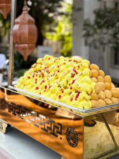 A mountain of fluffy Dahi Bhallas ready for a wedding feast. The soft lentil dumplings are topped with creamy yogurt, sweet and spicy chutneys, and pomegranate seeds, creating a refreshing and flavourful chaat.