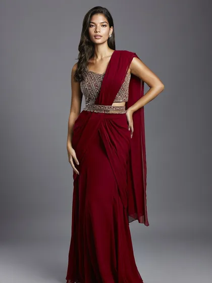 A stunning maroon draped saree with a heavily embellished blouse and belt, a glamorous choice for a reception or cocktail party.