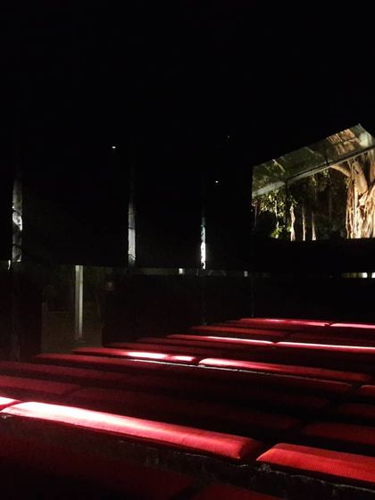 A view of an installation for the India Arch Dialogue event. The design uses darkness, focused openings, and the color red to create a dramatic, immersive space that explores the power of light and void in architecture.