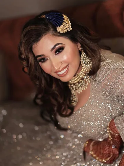 A happy and glowing sangeet bride. The bold eye makeup and luminous skin create a stunning look that is perfect for the festive atmosphere.