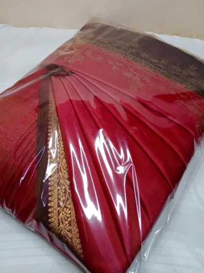 A beautiful red saree, pleated and sealed for delivery. You can send your sarees via a delivery service or drop them off yourself.