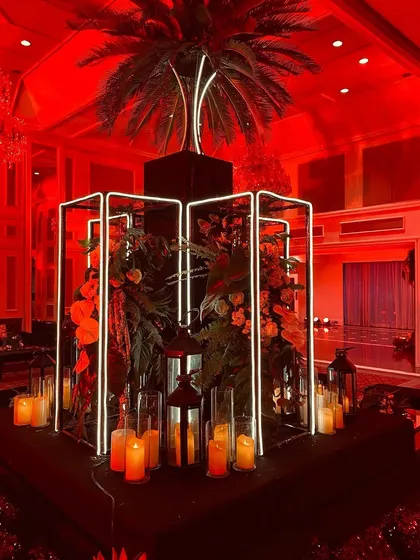 A centerpiece installation with tropical foliage lit by neon frames, continuing the bold, modern theme.