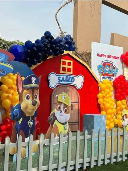 A closer look at the Paw Patrol setup, featuring character cutouts of Chase and Rubble against a red barn backdrop personalized with the birthday boy's name.