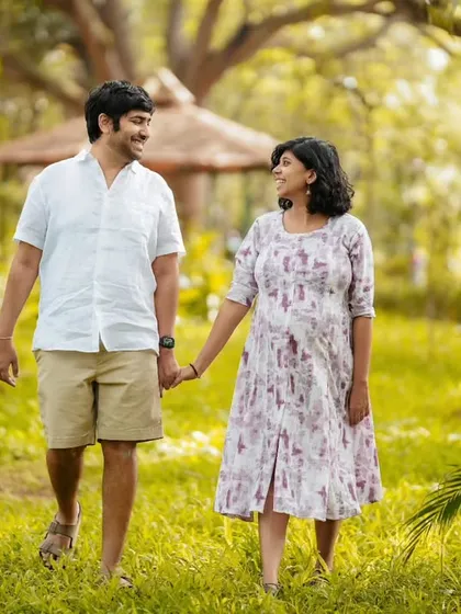 A happy, candid moment as a couple walks hand-in-hand through a sunlit park. Their smiles show the joy and excitement of this special time.