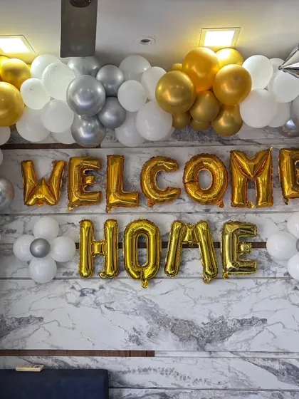 A classic 'Welcome Home' decoration with gold foil letters. We created a full balloon garland on the wall using gold, silver, and white balloons to make a bold and celebratory statement.