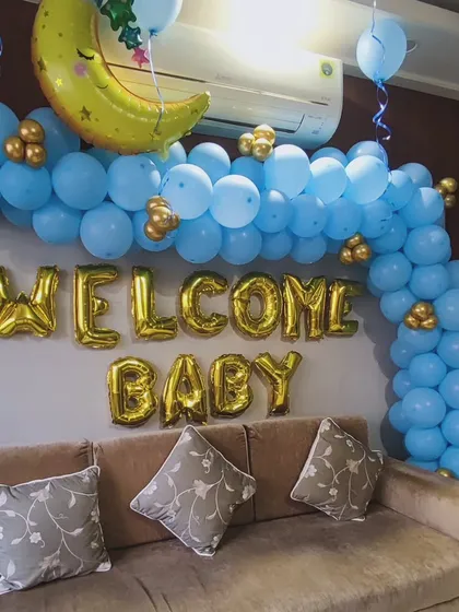 A simple and sweet 'Welcome Baby' decoration to greet a newborn. I used a blue balloon half-arch with small gold balloon accents, a crescent moon foil balloon, and large gold foil letters to create a warm welcome right in the family's living room.
