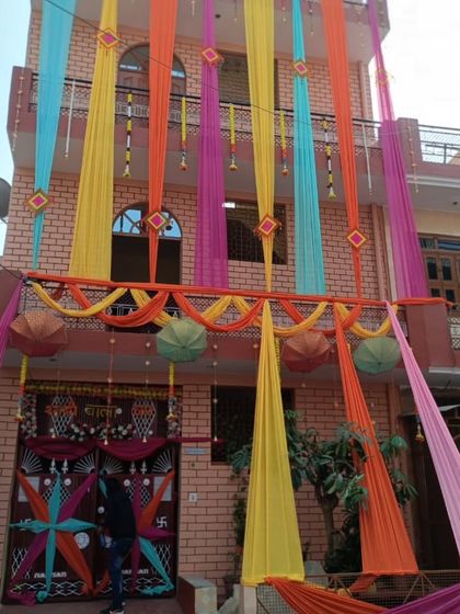 A full facade decoration with colorful drapes in yellow, pink, orange, and blue. This creates a vibrant and joyful look for the wedding house.