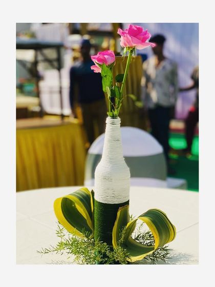 Sometimes, a simple design is best. For this sangeet event table, I used a recycled bottle wrapped in thread as a vase for two beautiful pink roses, with some decorative leaves at the base. It is simple, but looks very classy.