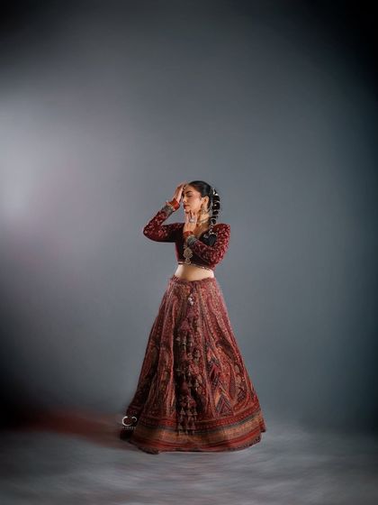 A pose that evokes classical dance and quiet contemplation. The lighting highlights the intricate details of her attire while her expression tells a story of inner peace.